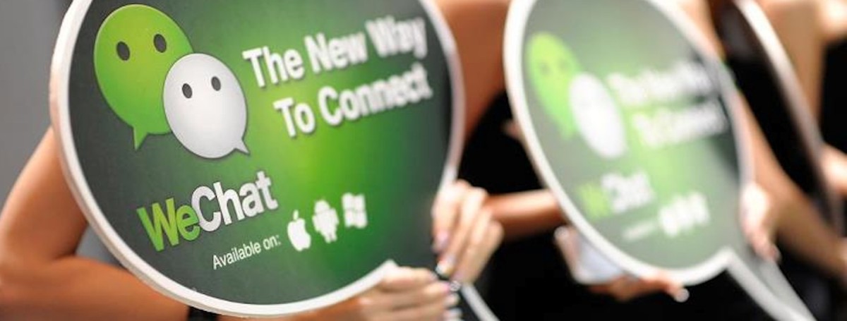 腾讯加大力度,大手笔拓展微信美国市场 two people holding promotion cards for wechat