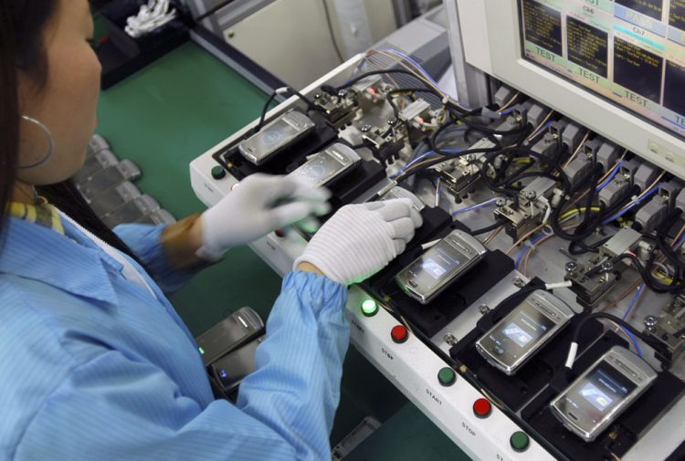 2017年中国生产了19亿部手机 worker assembling mobile phones at factory in china