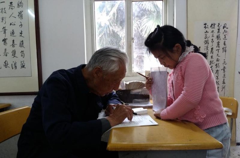 90岁退休老师18年来免费教学生英语 side view of old man giving class to young girl