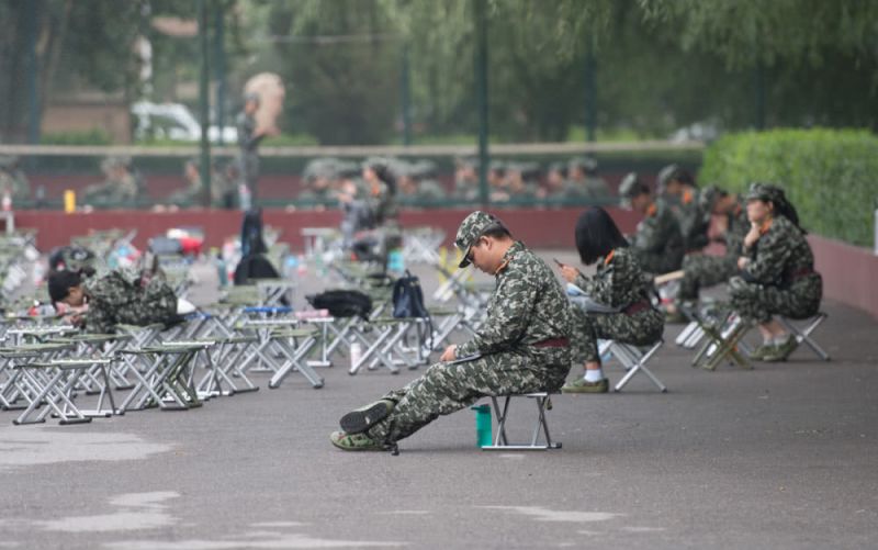 大学新生军训喊累 坐下休息玩手机 students sitting down with mobile phones during military training in china