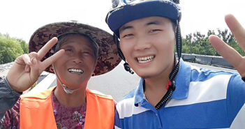 大学生骑行1300千米宣传环保 student cyclist posing for photo with sanitation worker