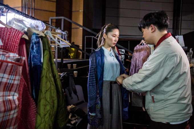 香港设计师回收废旧布料制成服装 man helping woman dress behind scenes of fashion show in hong kong