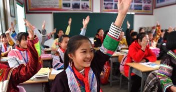 网络给广西一小学带来第一堂英语课 children raising hands in classroom in china