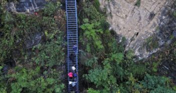“悬崖村”变身为旅游景点 people climbing steel ladder on side of cliff in china