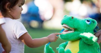 小女孩在浴缸里给鳄鱼刷牙 girl brushing toy crocodile's teeth